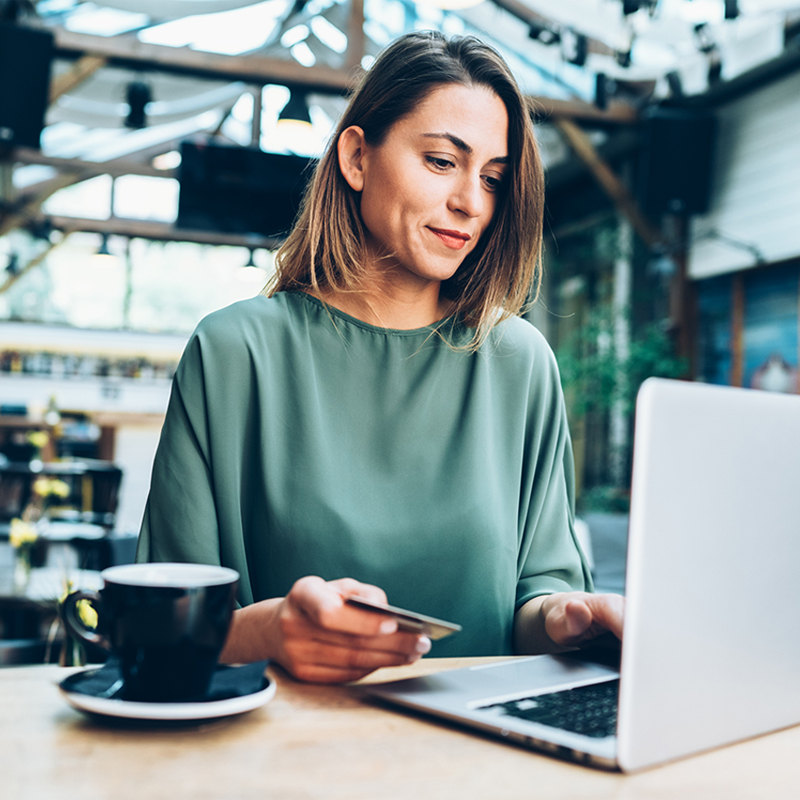 Young woman shopping online in cafe using lap top and credit card